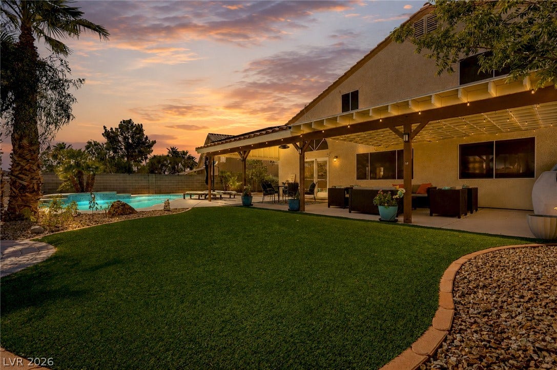 206 Oleander Place, Henderson, NV 89015 An inviting outdoor living area features a covered patio, a manicured lawn, and a sparkling pool, perfect for entertaining.