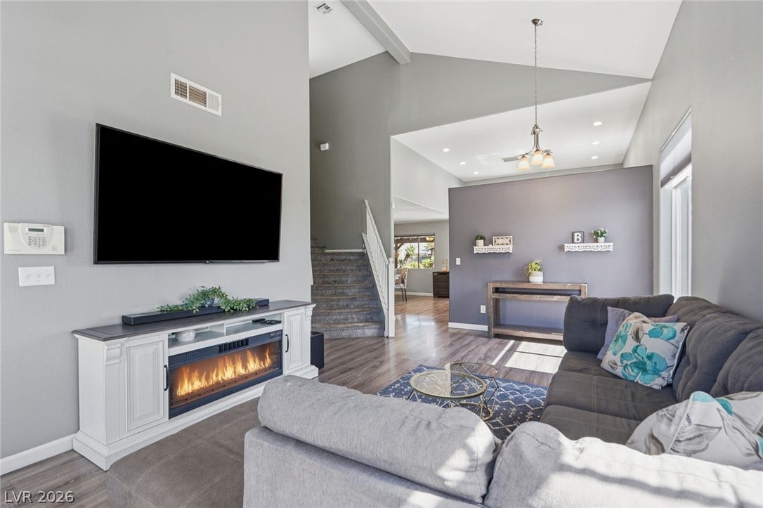 206 Oleander Place, Henderson, NV 89015 The open-concept living area features vaulted ceilings, rich wood-look flooring, and a modern electric fireplace.
