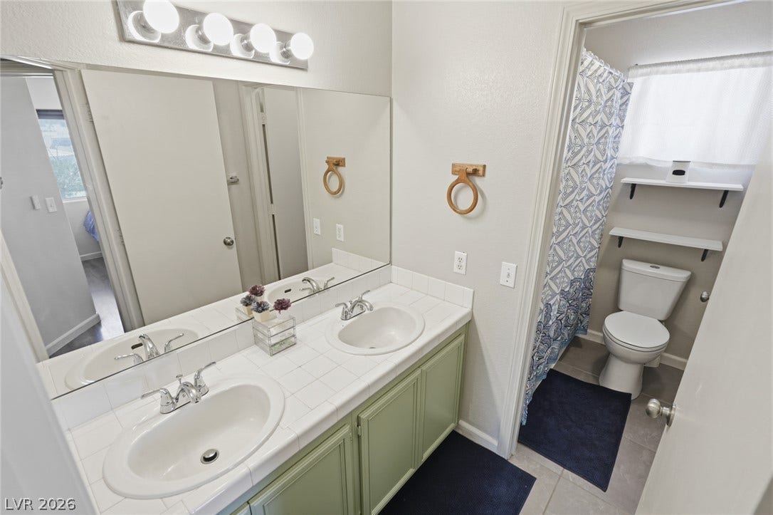 206 Oleander Place, Henderson, NV 89015 Double vanities and modern light fixtures create a refreshed atmosphere in this full bathroom.