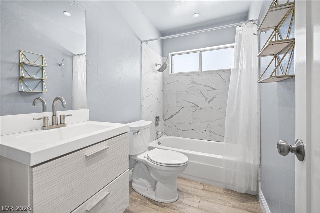 3303 Royce Court, Las Vegas, NV 89121 Step into a refreshed bathroom featuring a vanity, toilet, and a sleek shower-tub combination with elegant tile surround.
