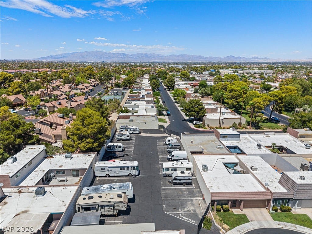 3303 Royce Court, Las Vegas, NV 89121 An aerial perspective reveals a residential community nestled against a distant mountain range, featuring a designated RV parking area.