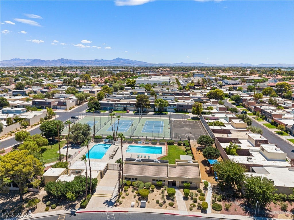 3303 Royce Court, Las Vegas, NV 89121 An aerial perspective reveals a vibrant community with recreational courts and inviting pools, all against a mountainous backdrop.