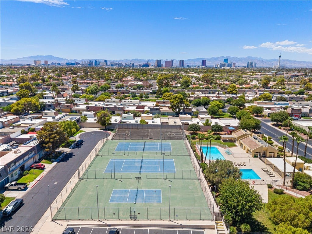 3303 Royce Court, Las Vegas, NV 89121 An aerial panorama reveals vibrant community tennis courts and refreshing pools set against a distant cityscape.