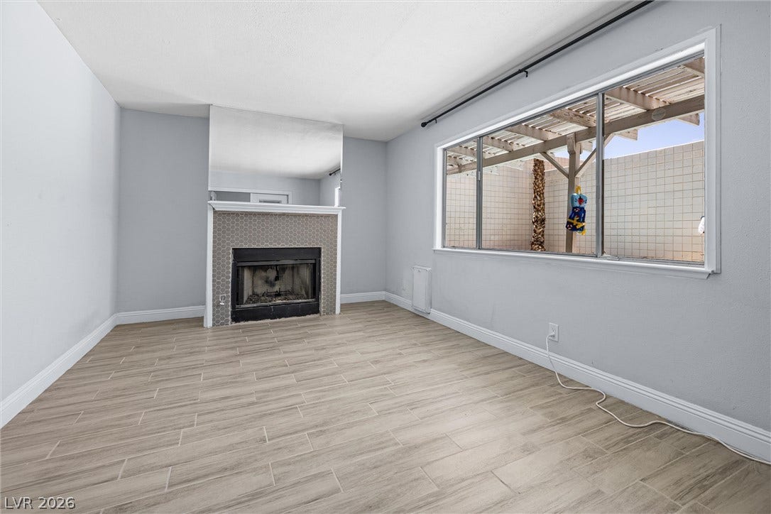 3303 Royce Court, Las Vegas, NV 89121 A cozy bedroom - living space features a charming fireplace with a hexagonal tile surround and a wide window overlooking a private patio.