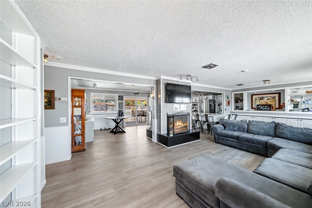A well-lit interior, complete with an inviting fireplace, flows seamlessly into the kitchen and beyond.