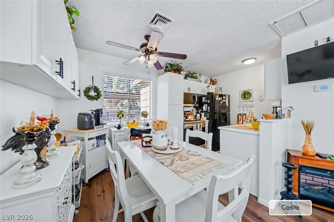 Rich wood-look flooring grounds this cozy dining area and kitchen space featuring a sunny window.