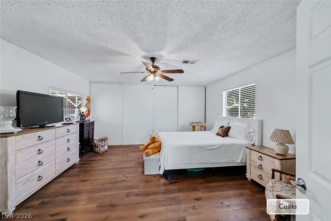 Rich wood-look flooring and generous closet space define this comfortable, light-filled bedroom.