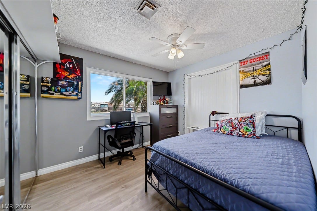 A window frames swaying palm trees and water views in this comfortable bedroom.