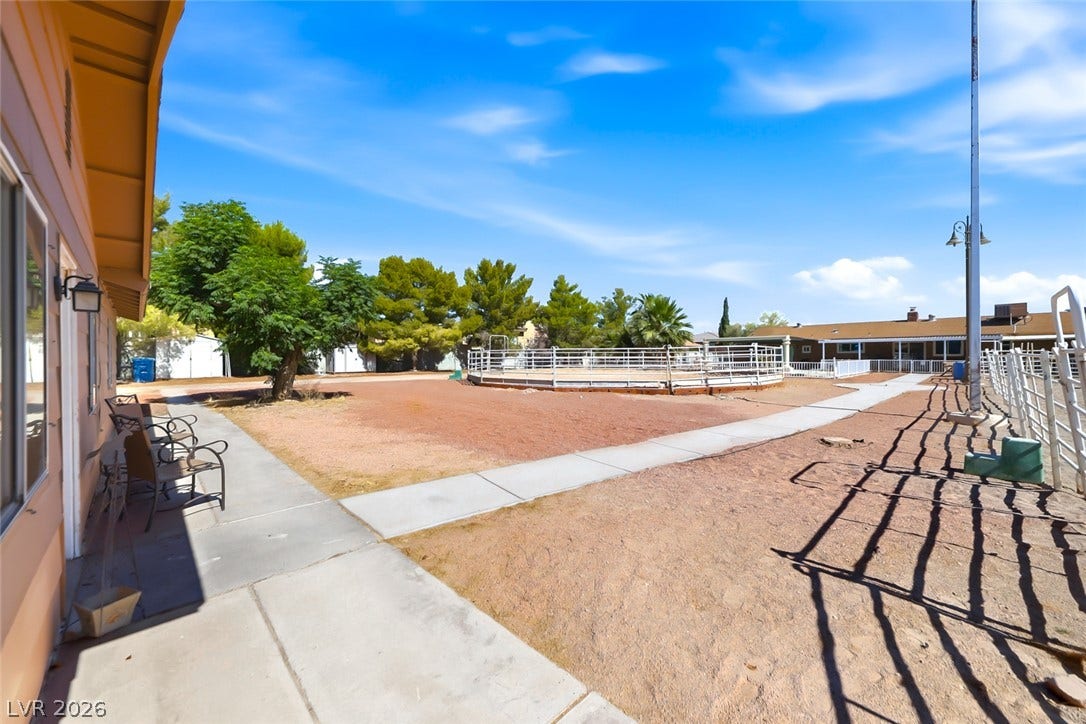 An equestrians dream, featuring a dedicated round pen and sprawling horse amenities under a bright sky.