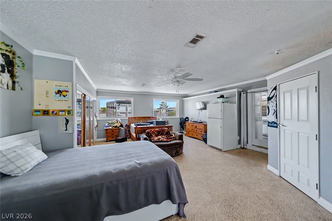 Oversized bedroom with soft carpet, a ceiling fan, and ample window light.