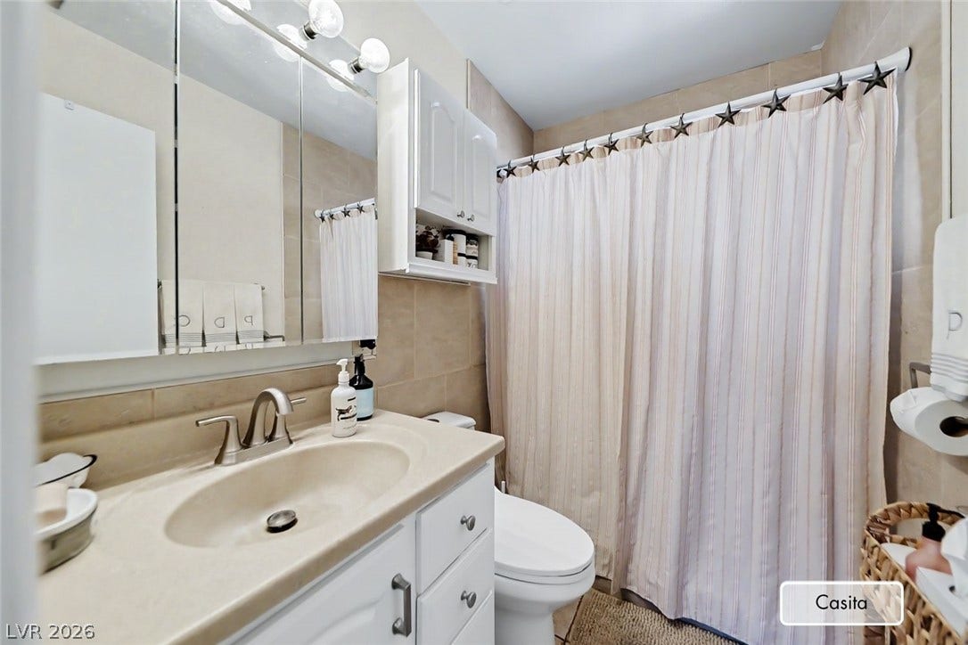 Tiled walls and a clean vanity with integrated sink define this functional bathroom space.