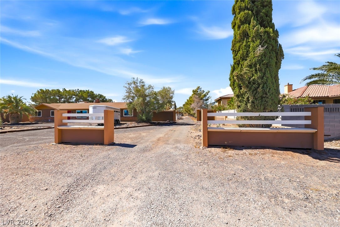 A private, fenced entrance with ample space leading to a sprawling residential property.