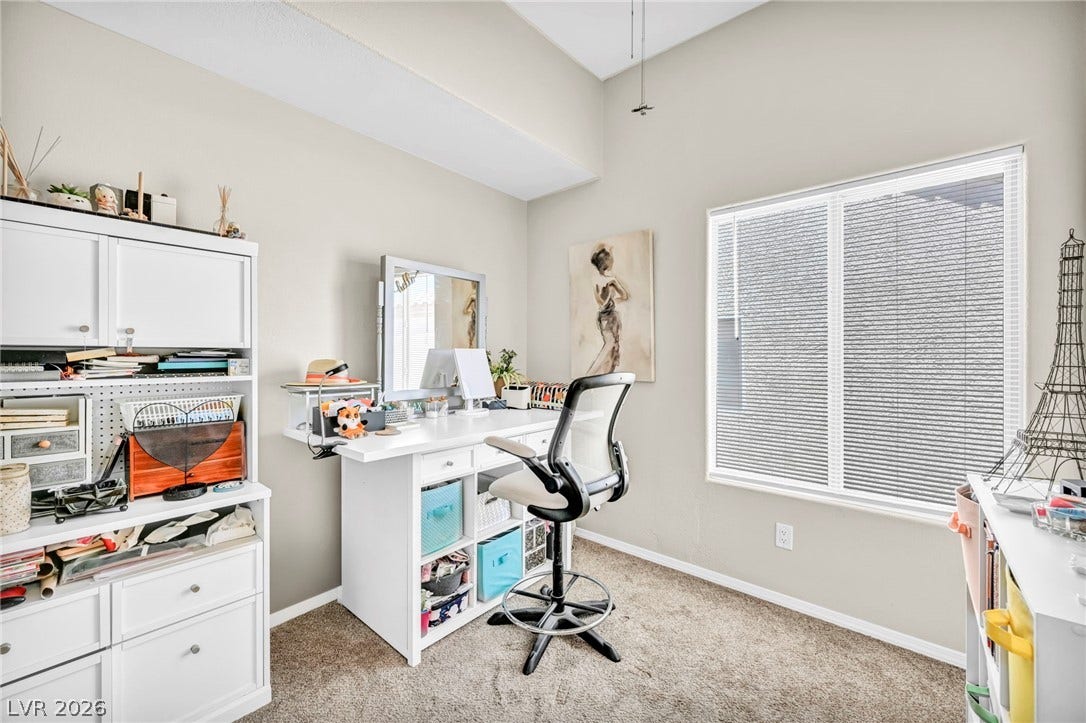 Well-lit office area with high ceilings and carpeted flooring offers a versatile workspace.