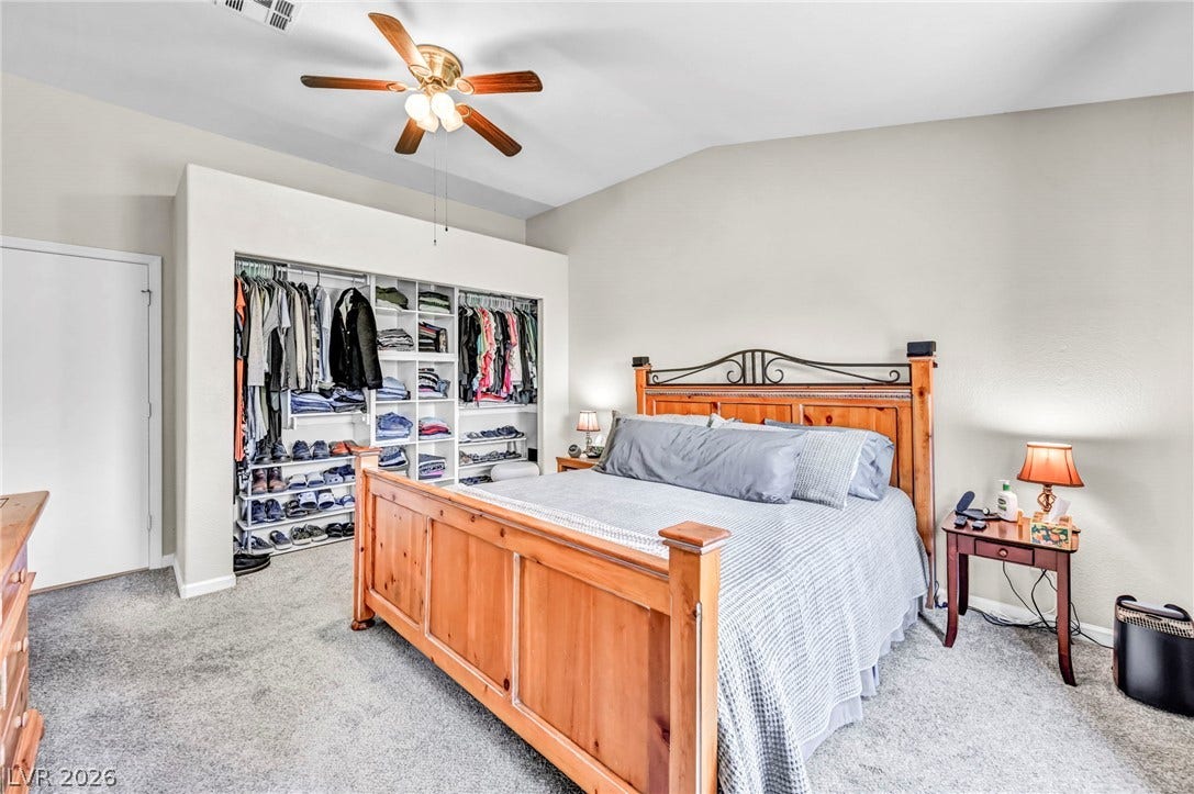This primary bedroom showcases vaulted ceilings and an organized, built-in closet system.