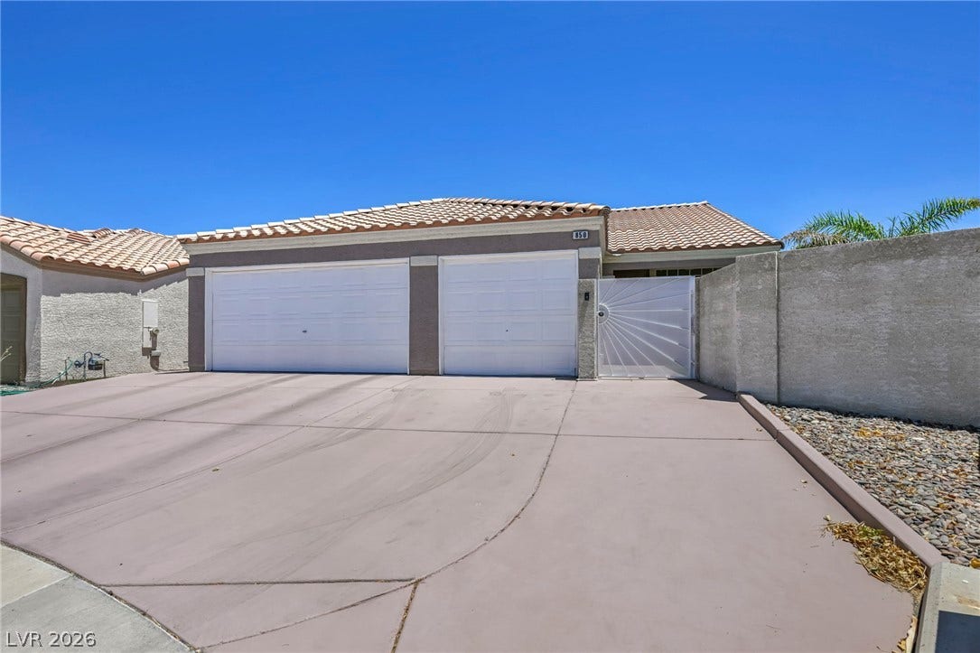 A well-maintained facade with two garage doors and a decorative gated entry.