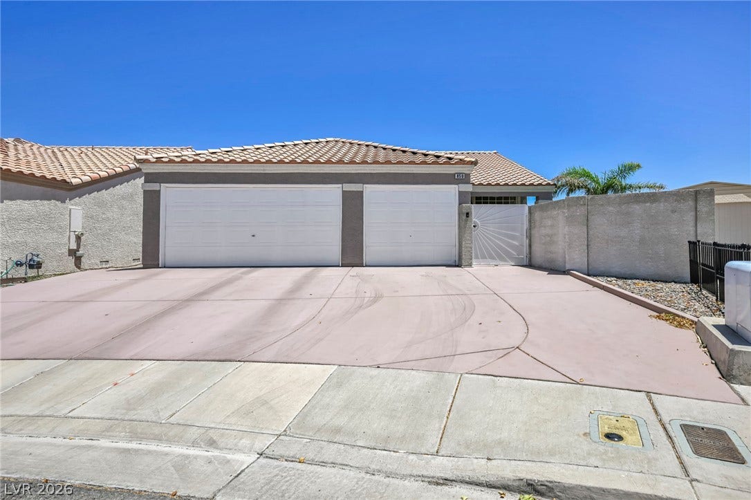 A spacious driveway leads to this home, featuring a gated entrance and a two-car garage.