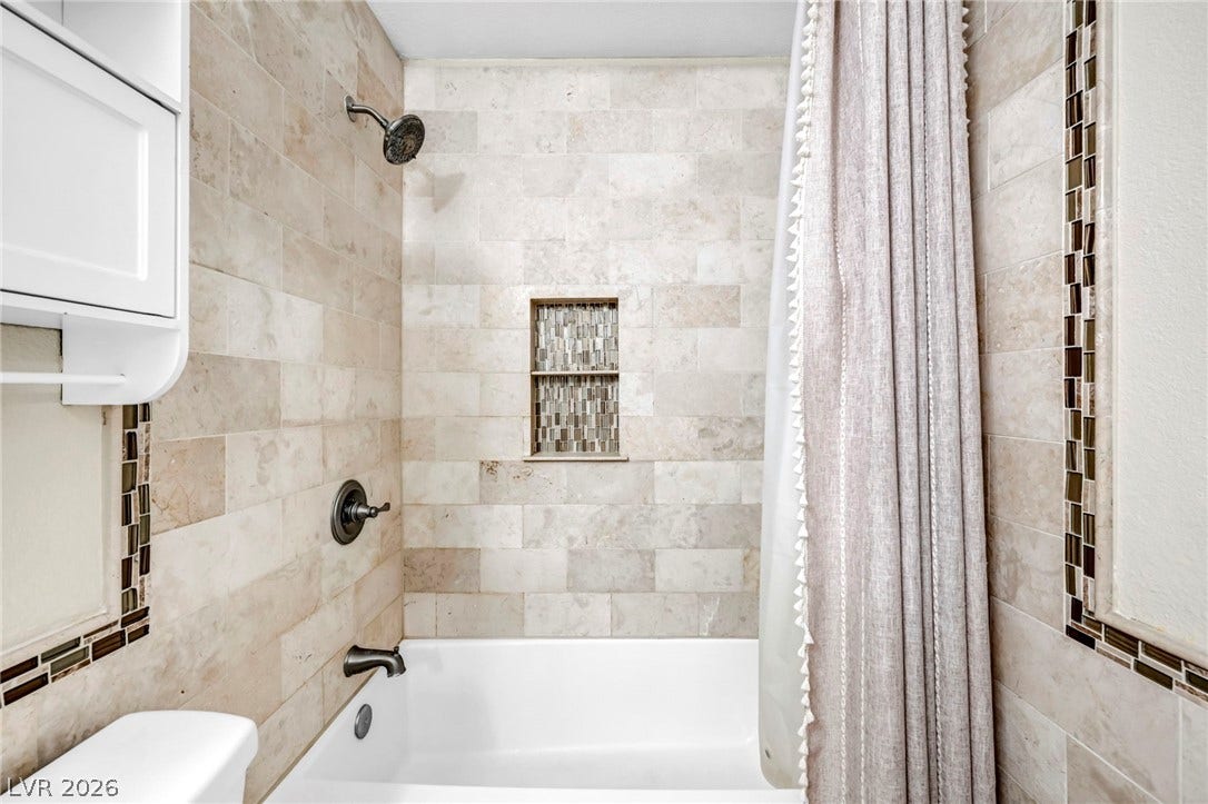 Tiled shower walls and a bathtub with a convenient recessed niche.