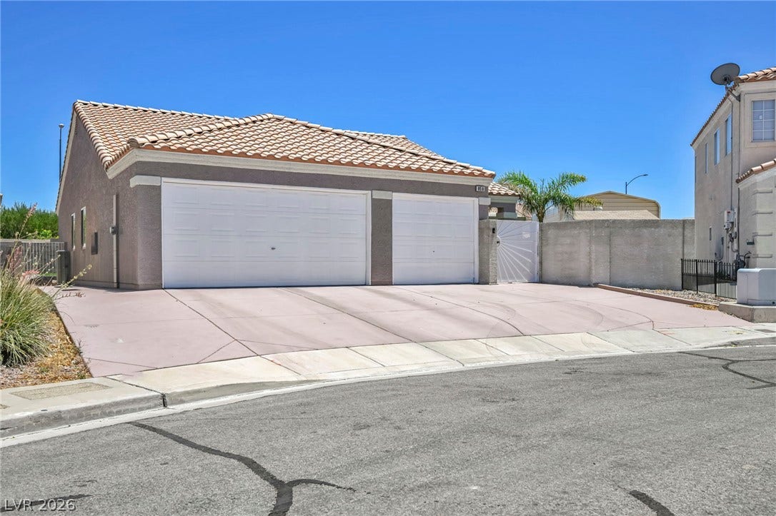 A pristine driveway leads to an attached two-car garage under a classic tiled roof.