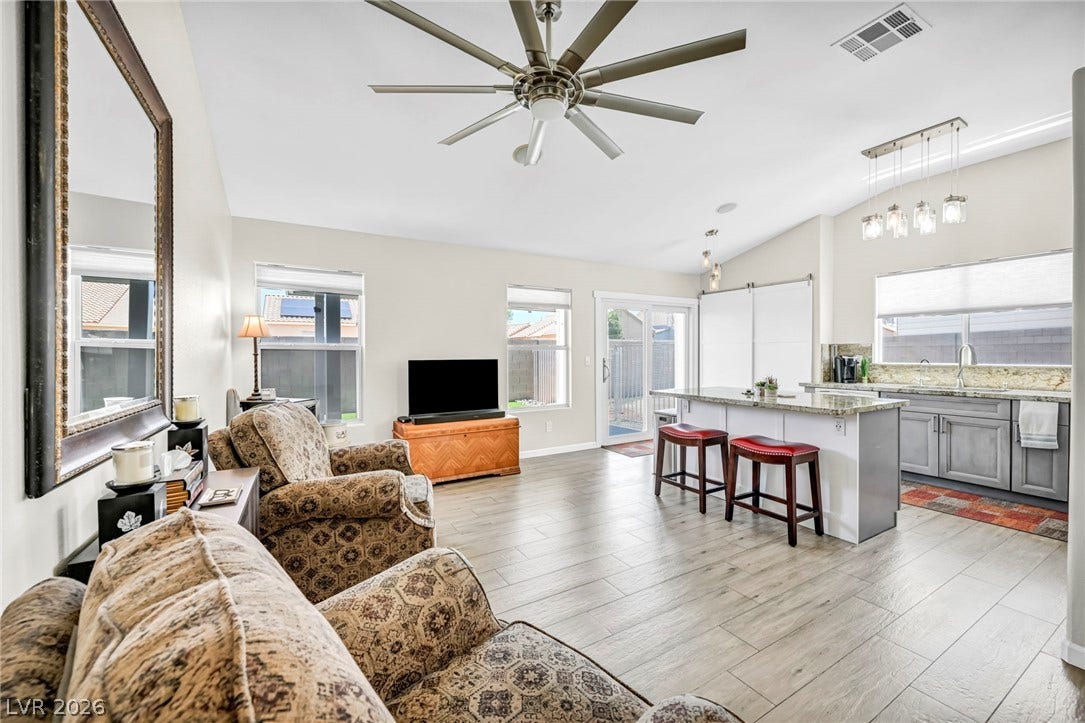 Vaulted ceilings amplify the open-concept living space, connecting the comfortable living area to a practical kitchen island.