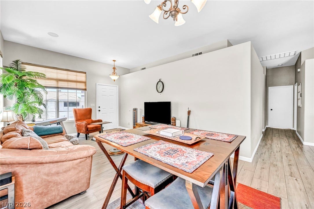 An inviting open-concept living and dining area features rich wood flooring and a classic chandelier.