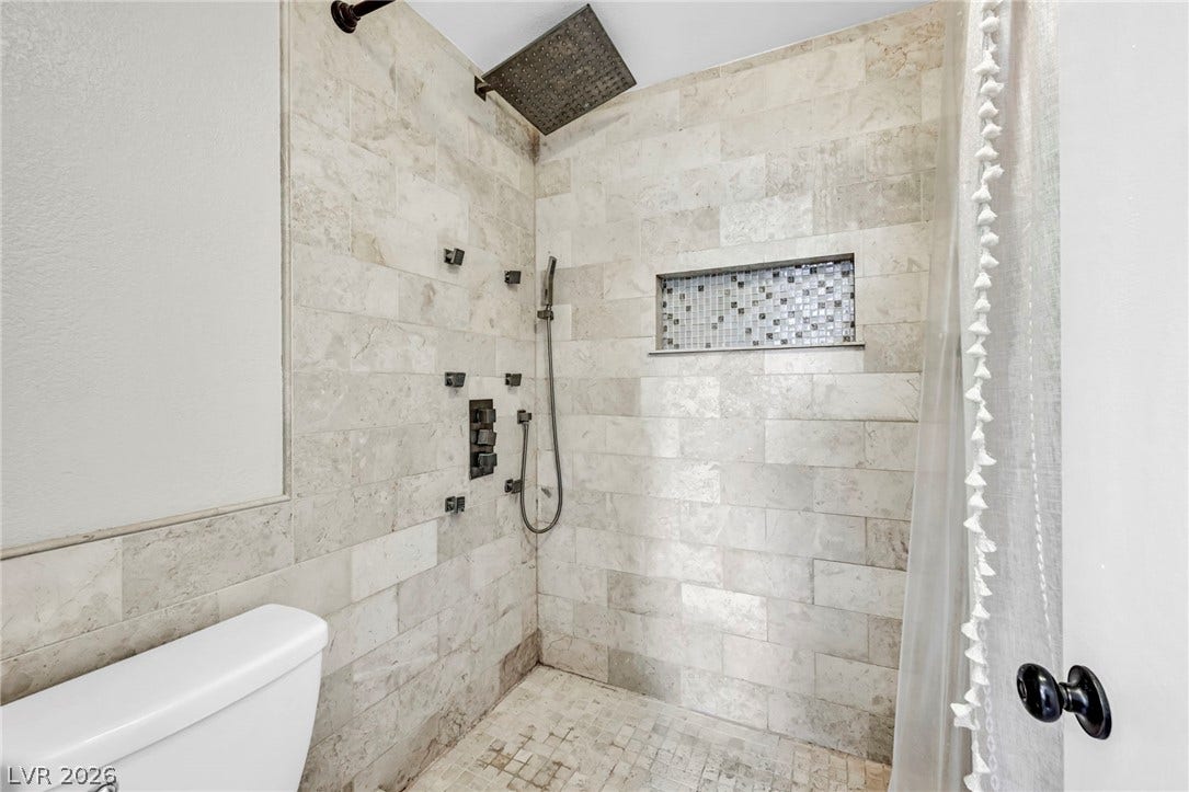 Luxurious walk-in shower with natural stone tile and multiple spray heads for a spa-like experience.