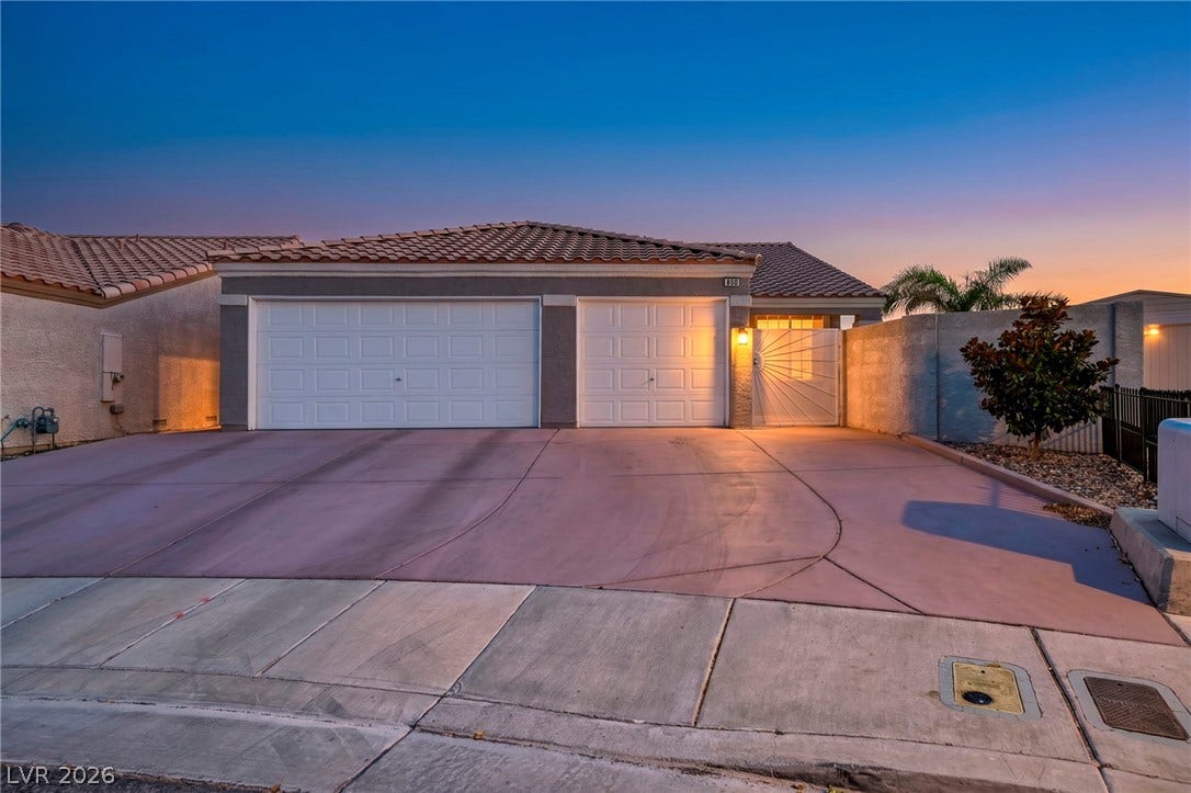 A welcoming facade showcases twin garages and an inviting entryway under a vibrant dusk sky.