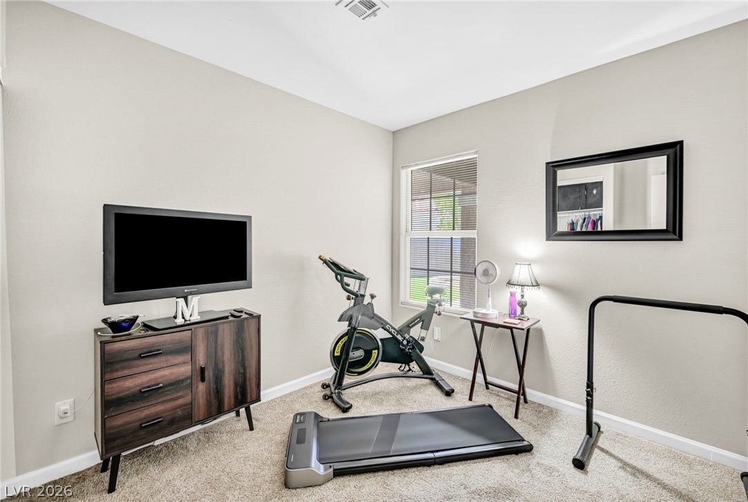 An inviting room provides versatile space for an exercise room or office, complete with soft carpeting and natural light.