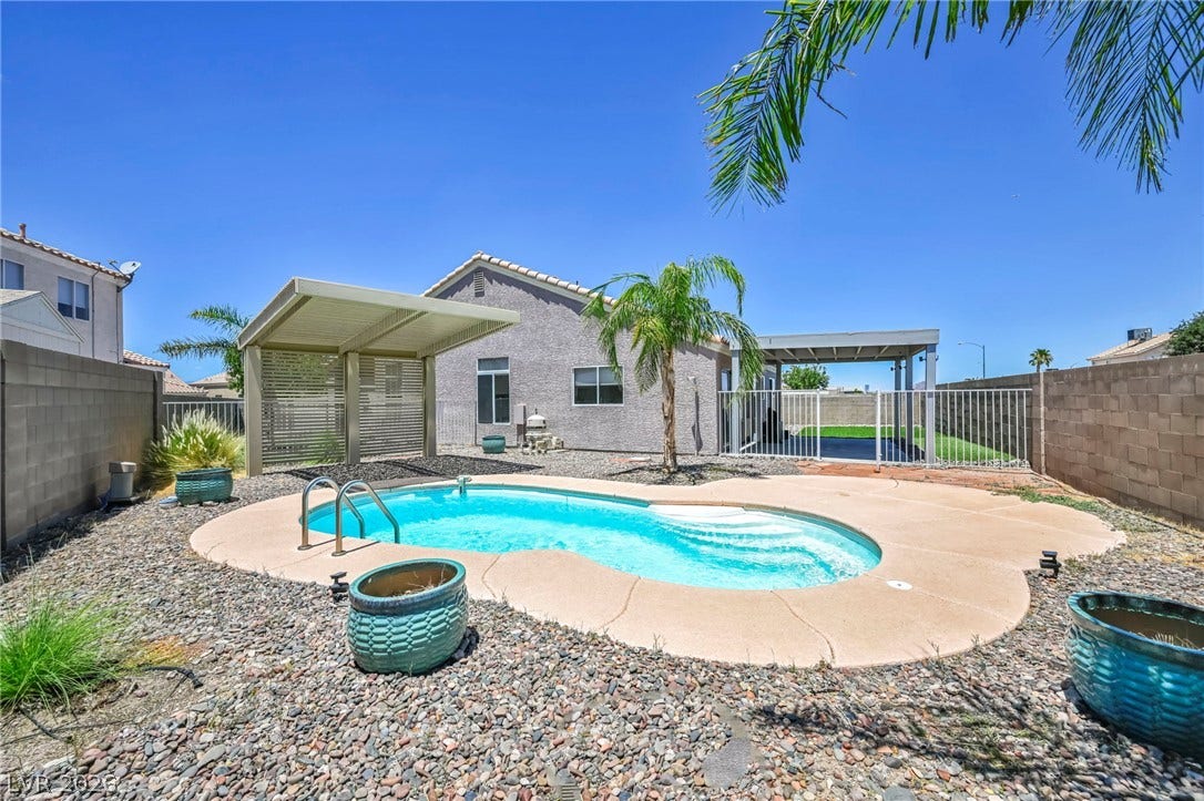 A tranquil backyard oasis features a freeform pool surrounded by low-maintenance landscaping and covered patio.