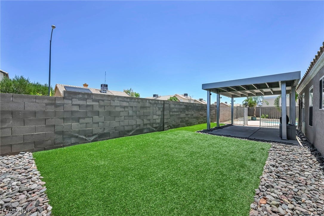 Green artificial turf and a covered patio create a low-maintenance outdoor sanctuary.