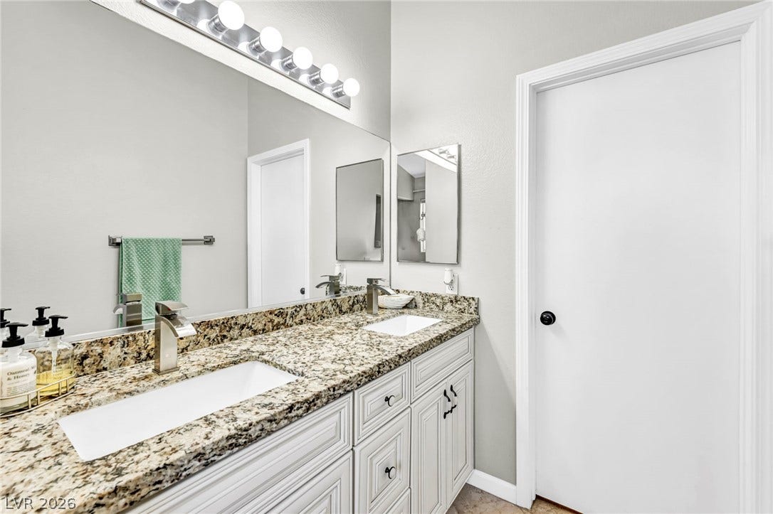 Double vanities with sleek fixtures provide ample space in this well-appointed bathroom.