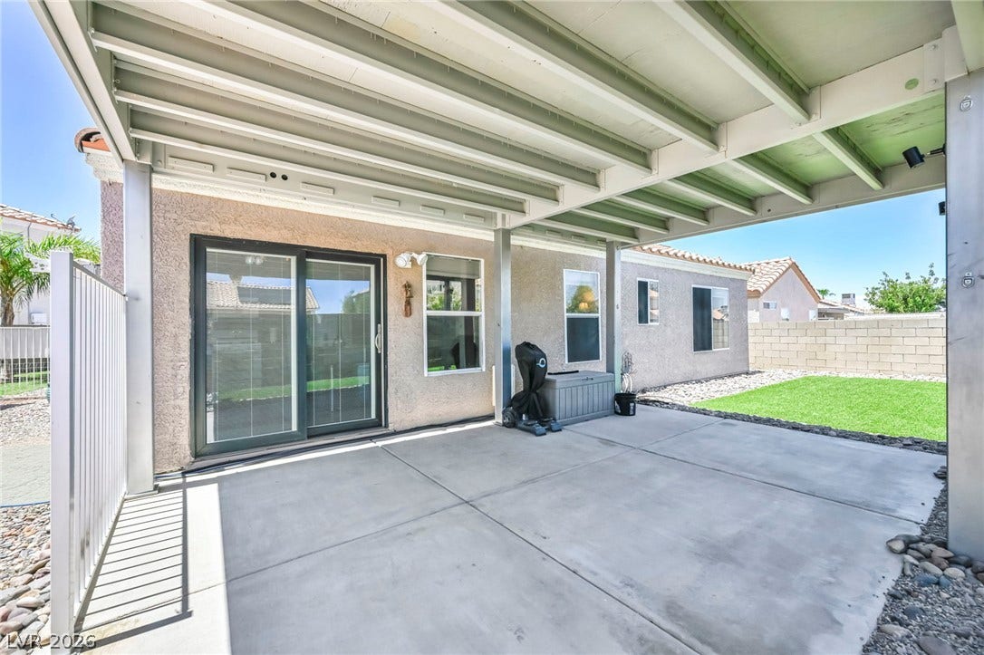 A spacious covered patio extends to a landscaped yard, perfect for outdoor living.
