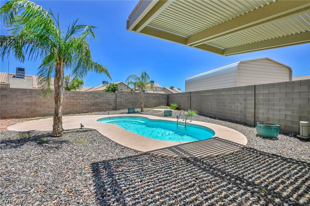 A tranquil backyard oasis featuring a free-form pool and ample sun-drenched lounging space.