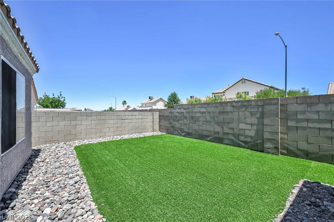 A low-maintenance yard, combining artificial turf with decorative rocks, offers a simple outdoor retreat.