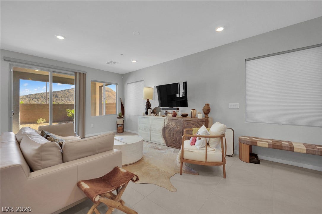 11572 Desert Hollow Avenue, Las Vegas, NV 89138 Sliding glass doors open to mountain vistas, providing abundant natural light to this inviting living space.