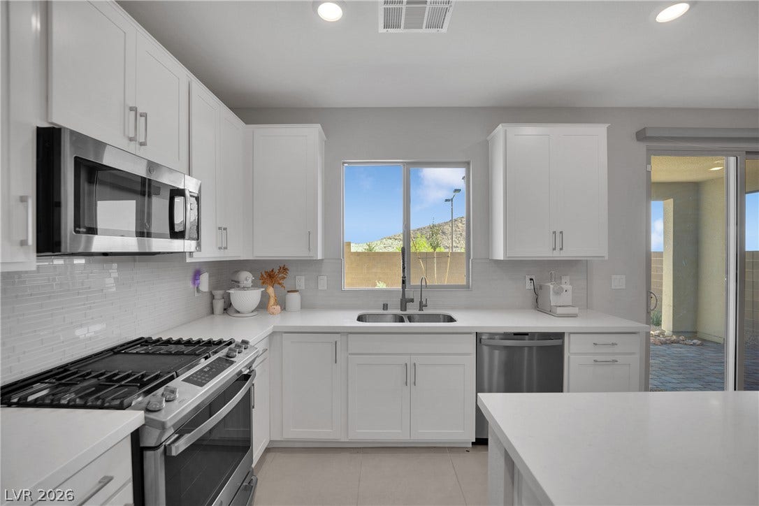 11572 Desert Hollow Avenue, Las Vegas, NV 89138 Gleaming white cabinetry and stainless steel appliances complete this bright, functional kitchen.