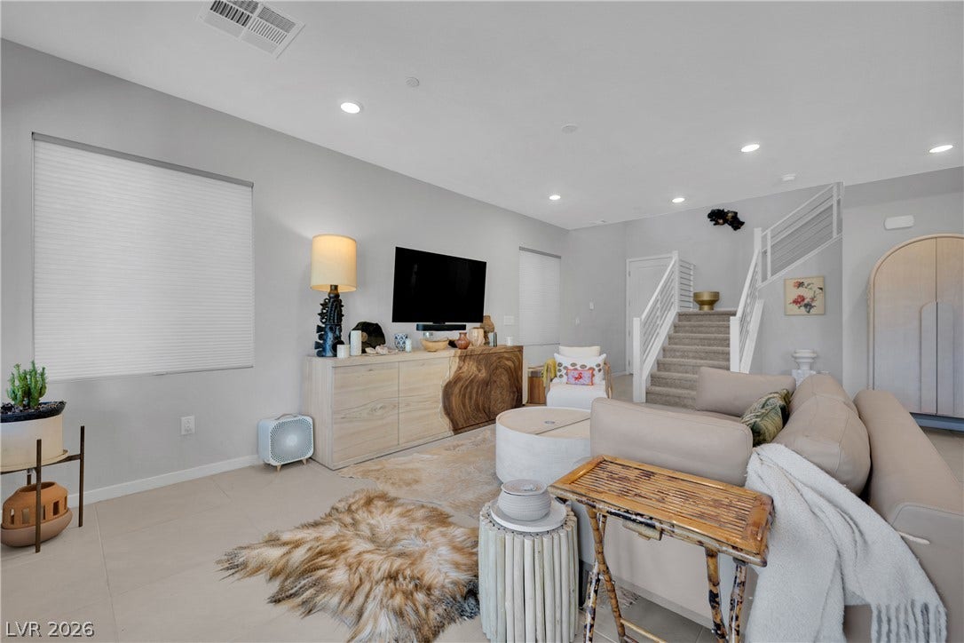 11572 Desert Hollow Avenue, Las Vegas, NV 89138 Recessed lighting illuminates an inviting living space with elegant flooring and a carpeted staircase leading to the upper level.