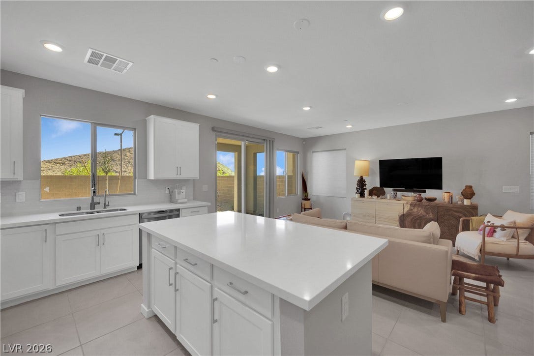 11572 Desert Hollow Avenue, Las Vegas, NV 89138 An open concept kitchen and living area with a bright white island and desert views from the windows.