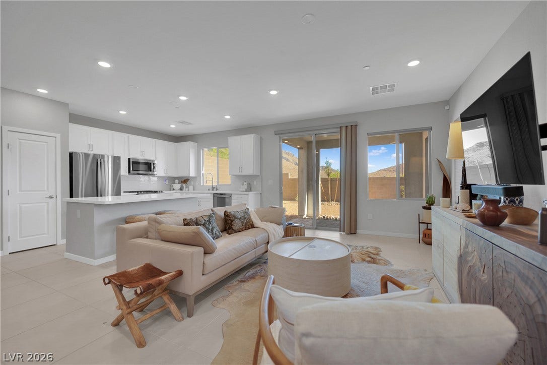 11572 Desert Hollow Avenue, Las Vegas, NV 89138 A versatile open-concept living space seamlessly connects the kitchen and outdoor patio through sliding glass doors.