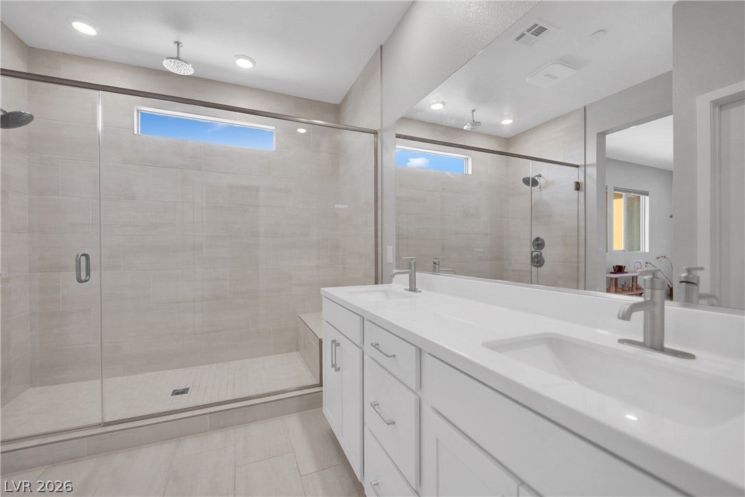 11572 Desert Hollow Avenue, Las Vegas, NV 89138 Dual vanities and an oversized glass-enclosed shower create a rejuvenating primary bathroom experience.