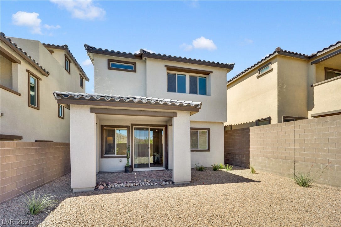 11572 Desert Hollow Avenue, Las Vegas, NV 89138 A private backyard oasis featuring a covered patio with brick pavers and surrounding gravel landscaping.