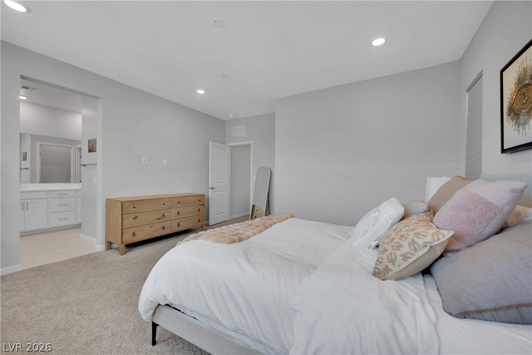 11572 Desert Hollow Avenue, Las Vegas, NV 89138 Well-lit primary bedroom features soft carpeting and direct access to a private bath.