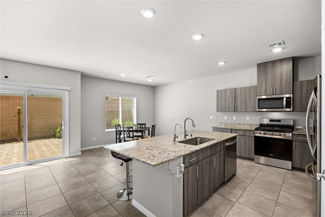 8943 Pelican Point Street, Las Vegas, NV 89178 A well-appointed kitchen and dining area feature granite counters and modern appliances, opening to a private outdoor patio.