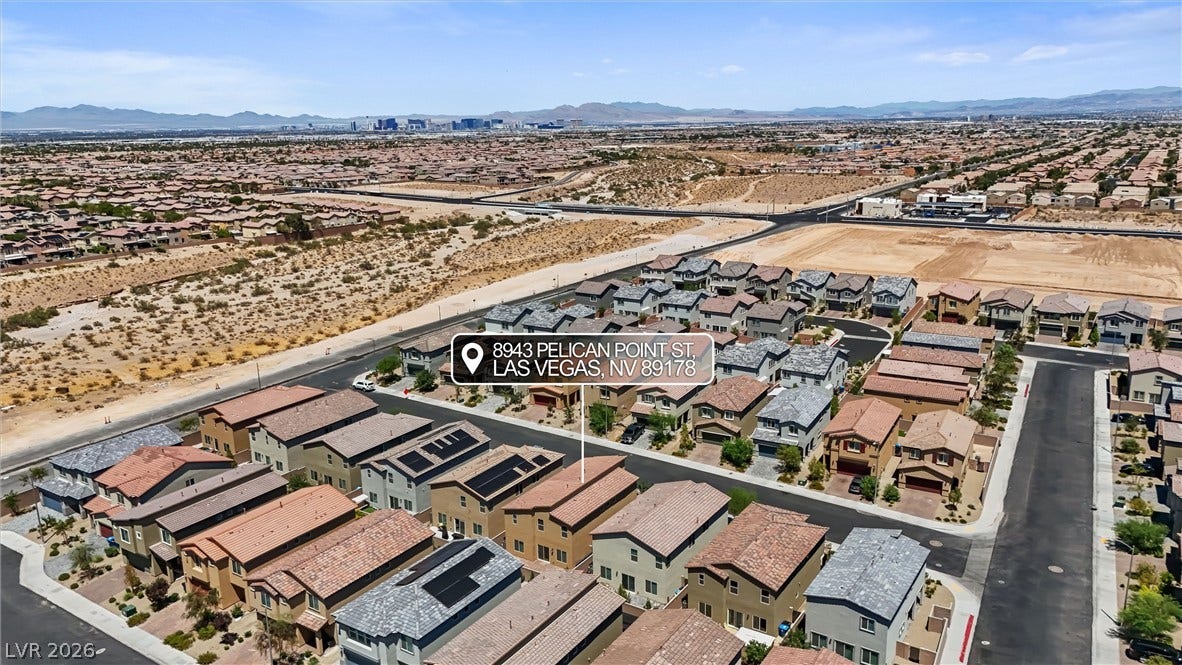 8943 Pelican Point Street, Las Vegas, NV 89178 An aerial panorama reveals a vast residential community with mountains and cityscapes in the distance.