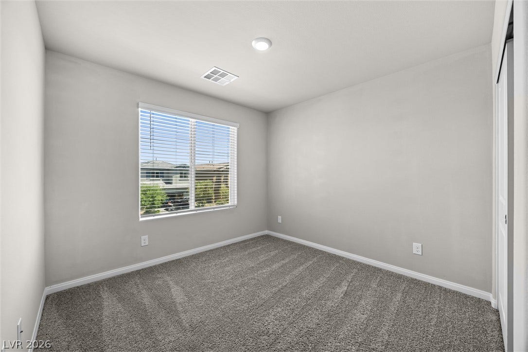 8943 Pelican Point Street, Las Vegas, NV 89178 A well-lit bedroom features plush carpeting and a wide window offering neighborhood views.