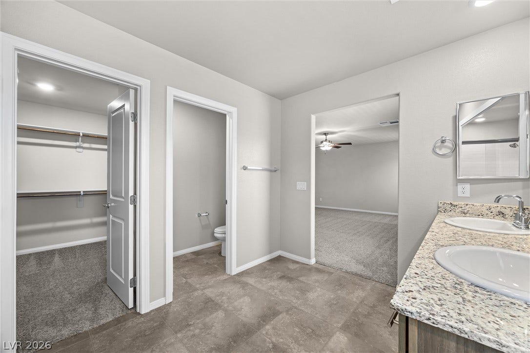8943 Pelican Point Street, Las Vegas, NV 89178 Granite counters and dual sinks define this functional primary bathroom, offering ample space and direct access to a roomy walk-in closet.