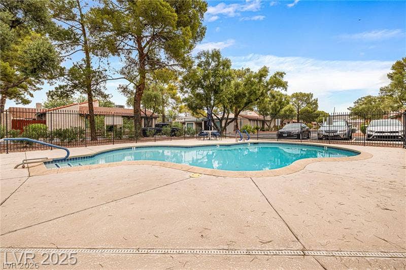 A refreshing pool awaits, perfectly framed by mature trees and a sturdy perimeter fence.