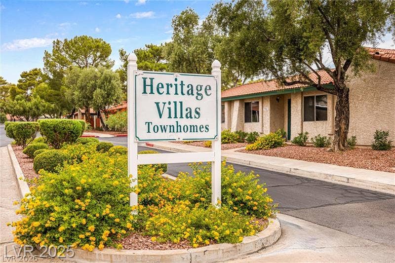Mature trees and vibrant landscaping frame the inviting entrance to this charming townhome community.