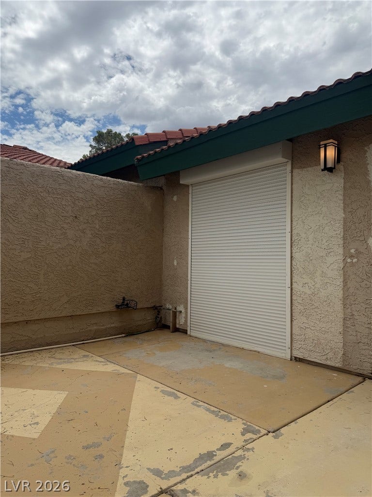 A private courtyard space, featuring durable stucco walls and a robust roll-down security shutter for peace of mind.