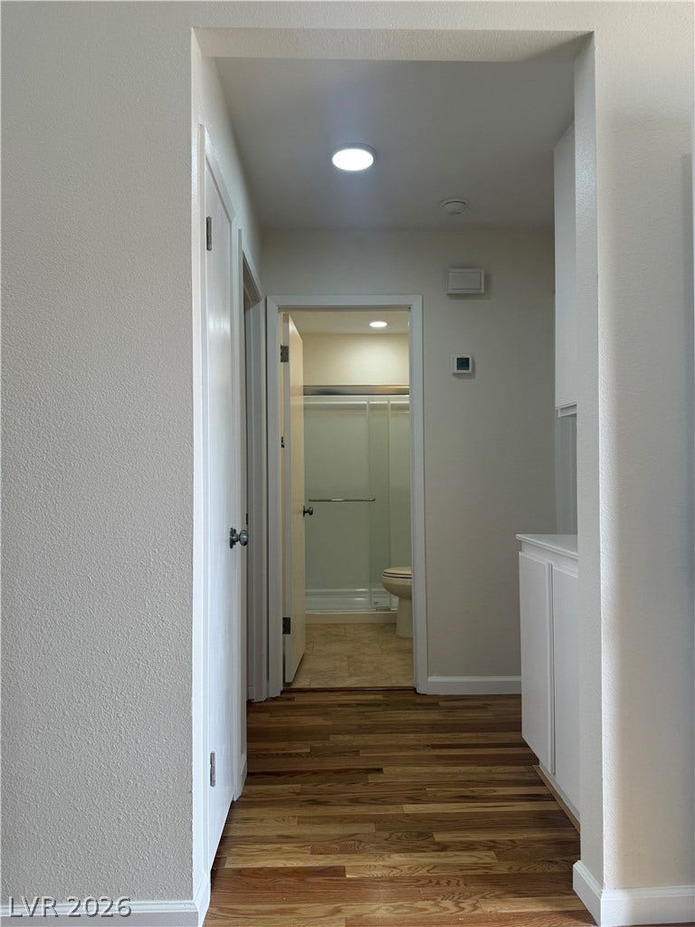 A streamlined hallway offers clear sightlines and easy access to a full bathroom.