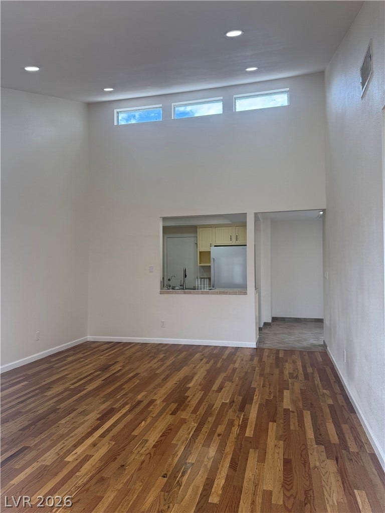 Natural light streams into this expansive living area, featuring rich hardwood floors and recessed lighting.